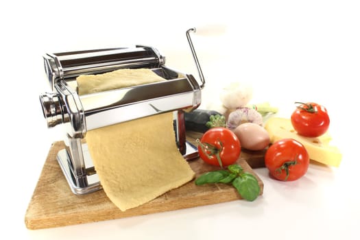 Noodle dough in a pasta machine with vegetables and basil