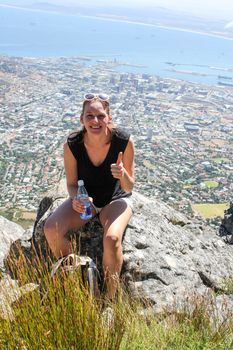 Woman resting while hiking in front of cape towns cityscape