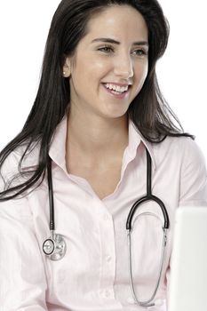 Beautiful young doctor sat smiling at her work desk using her computer.