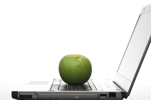Open laptop sideways on with a fresh red apple creating a elearning concept.