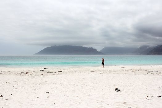 Woman walking along the Beach of Kommetjie with an upcoming storm in the background