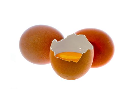 close up on two raw eggs, one broken, one whole isolated on white background