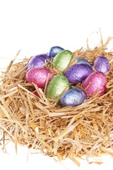 Straw nest with chocolate Easter eggs over white studio shoot