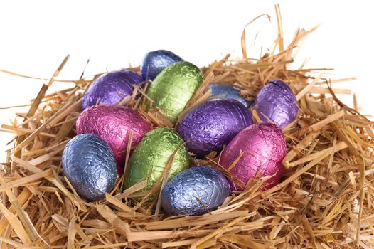 Straw nest with chocolate Easter eggs over white studio shoot