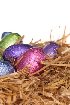 Straw nest with chocolate Easter eggs over white studio shoot