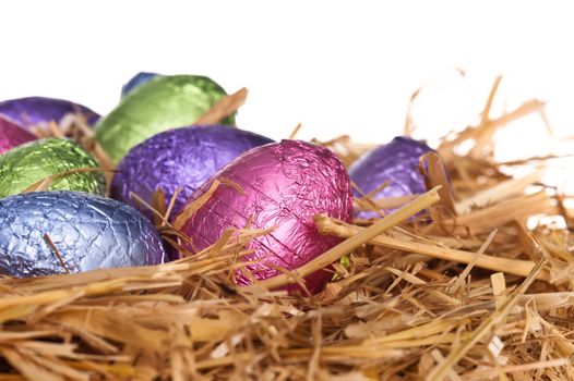 Straw nest with chocolate Easter eggs over white studio shoot