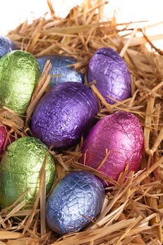 Straw nest with chocolate Easter eggs over white studio shoot