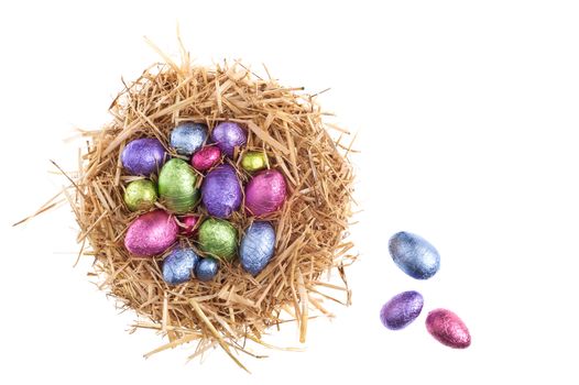 Straw nest with chocolate Easter eggs over white studio shoot