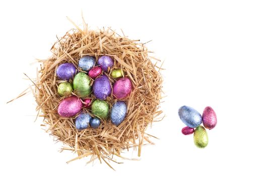 Straw nest with chocolate Easter eggs over white studio shoot