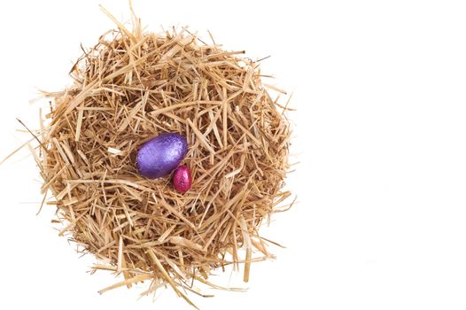 Straw nest with chocolate Easter eggs over white studio shoot