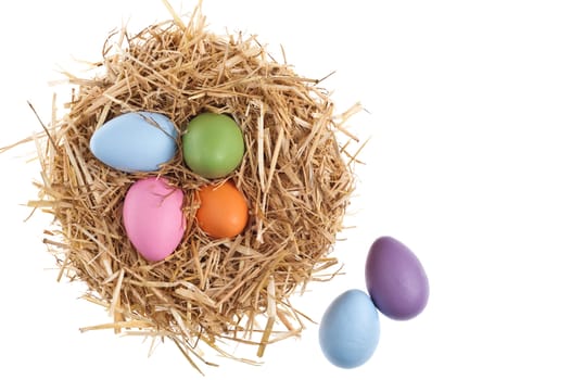 Straw nest with nice colored Easter eggs over white studio shoot