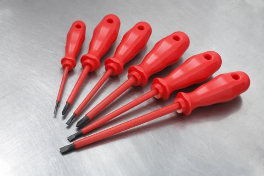 A Set of new electrician's insulated screwdrivers on scratched metal surface
