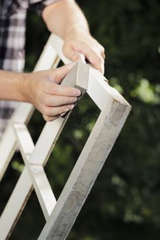 Man using Abrasive foam Block on an old window frame outdoors.