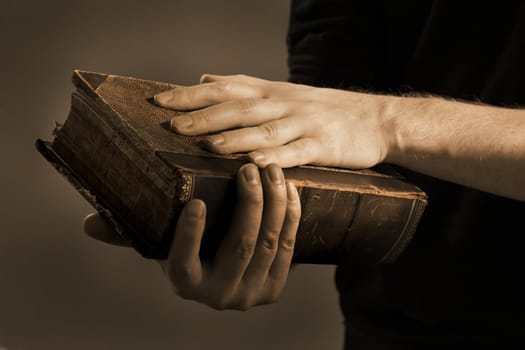 Toned image of a Man holding an old book in his hands.
