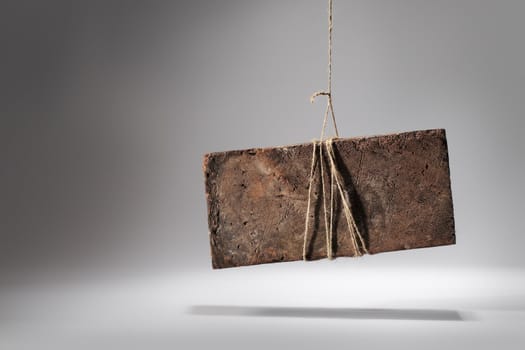 Old worn and weathered brick hanging by a string.
