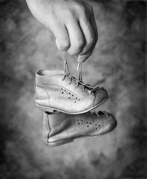Black and white image of Man holding his old baby shoes in his hand.