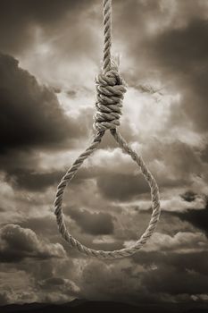 Sepia toned photograph of a hangman's Noose against cloudy sky.
