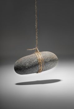 Conceptual image of a small rock hanging on a string.