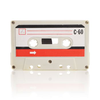Old compact cassette audio tape isolated on white 
with natural reflection.