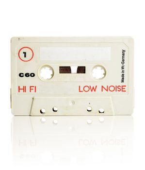 Old Compact cassette audio tape isolated on white with natural reflection.