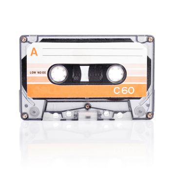 Old compact cassette audio tape isolated on white with natural shadow.