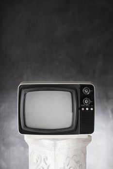 Old small portable television on a plaster column.