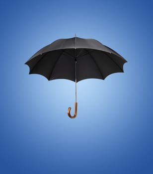 Old black vintage umbrella against blue background.