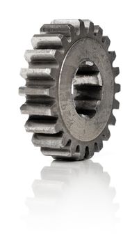 Old metallic cog gear wheel on white, with natural reflection. Short depth-of-field.