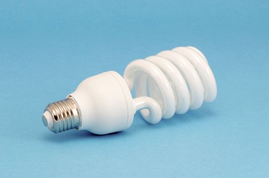 Novel fluorescent light bulb on blue background. New technology for less electricity energy consumption.