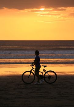The woman with a bicycle on a coast of ocean