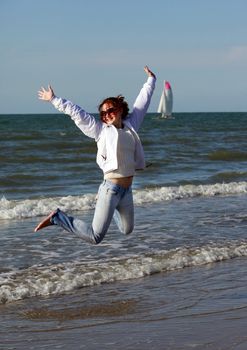 Happy woman enjoying her time at the beach and jumping