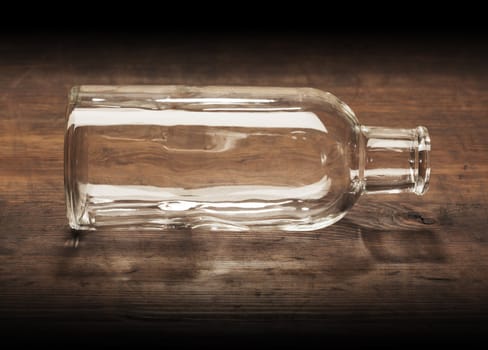 Old-fashioned empty glass bottle on wooden table.