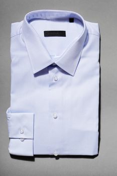 A light blue new men's dress shirt on grey background.