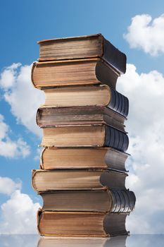 Old books in a stack with sky background.