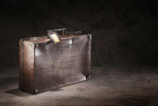 Old brown suitcase with a name tag.