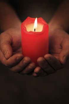 Man holding a red candle in his hands. Very short depth-of-field.
