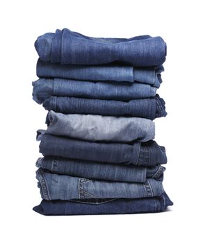 Stack of blue jeans pants isolated on white with natural shadows