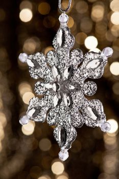 Artificial Snowflake in Silver shining over a golden background