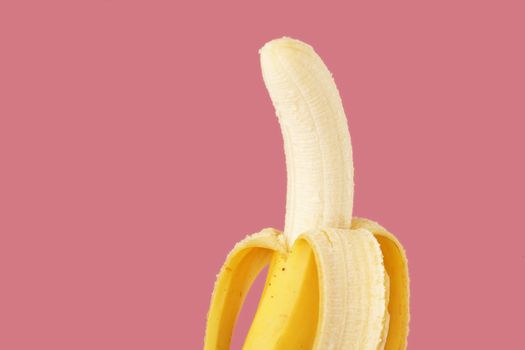 A banana ready for eating on pink background