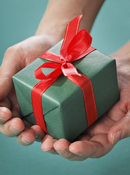 Man holding a small green gift with red ribbon