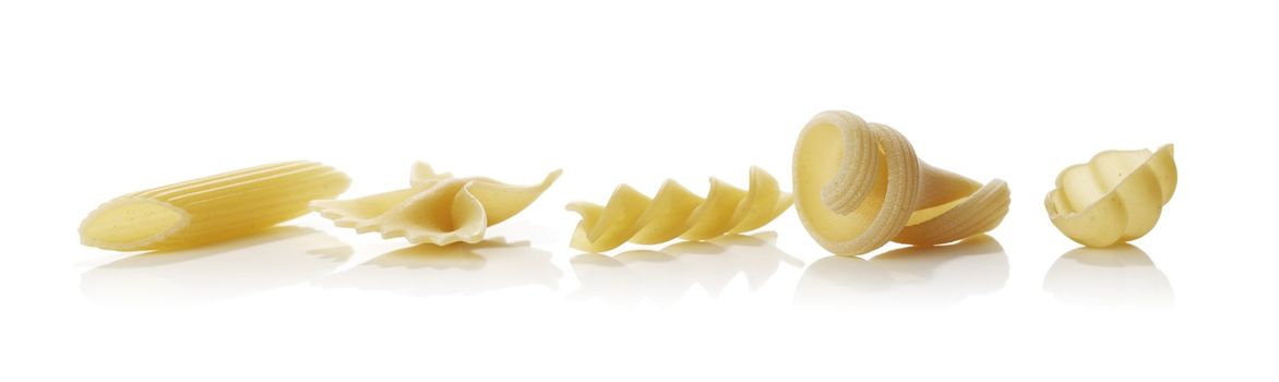 Different shapes of raw dried pasta isolated on white with reflections.