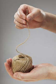 Hand holding a roll of natural fibre string