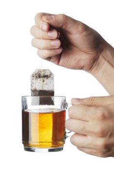 Hand lifting an used tea bag from a transparent tea mug