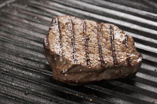 Beef tenderloin steak with pepper on a grill pan.