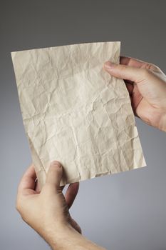 Man holding an old crumpled paper in his hands.