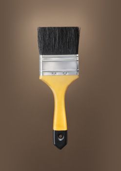 Yellow paint brush on brown background