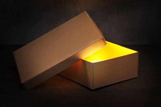 An Old brown cardboard box with glowing contents.