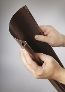 Man holding old-fashioned brown piece of rain gutter in his hands