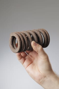 Man holding an old rusty metallic spring coil in his hand.