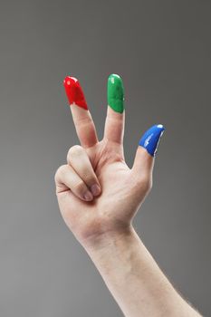 Fingers with fingerpaints in three primary colors, Red, green and blue.